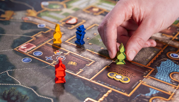 Official MinaLima gameplay image showing Defenders of Hogwarts pieces moving on the board.