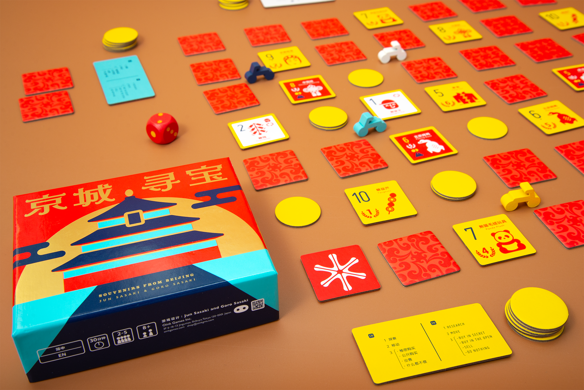Souvenirs from Beijing spread across a table with souvenir tiles, coins and a Chinese-English reference card.