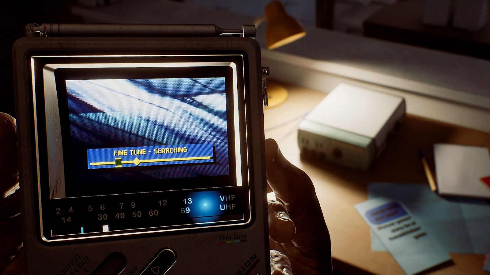 Official Silent Hill: Townfall gameplay image showing the CRTV aimed toward an object in a dim interior.