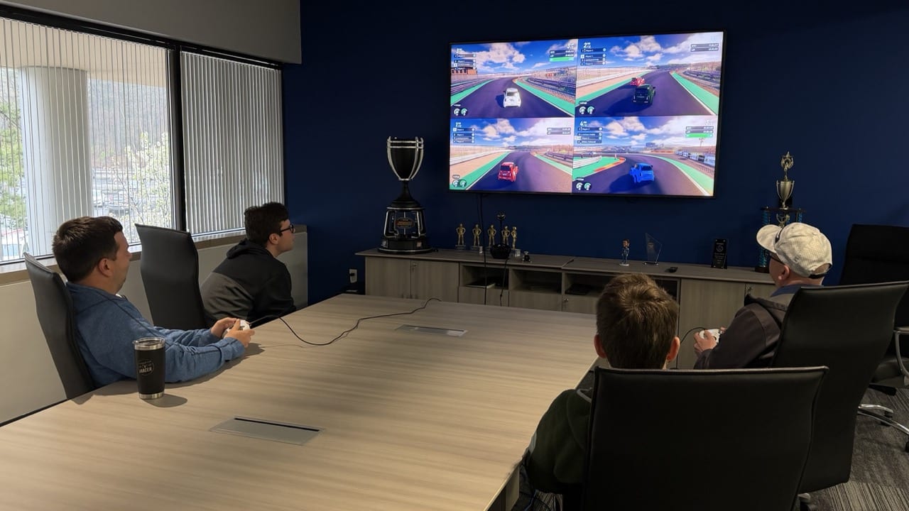 Official iRacing Arcade image showing four-player local split-screen racing on a couch-oriented setup.