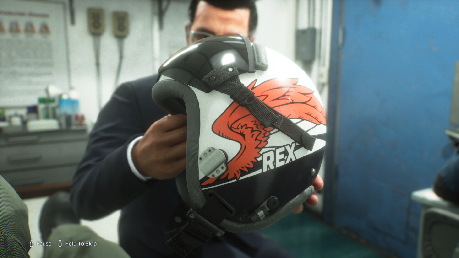 A person holds a pilot helmet with a red dragon graphic and REX lettering.